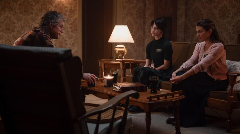 Thatcher as Sister Barnes and Chloe East as Sister Paxton talking to Hugh Grant as Mr. Reed in a living room in Heretic