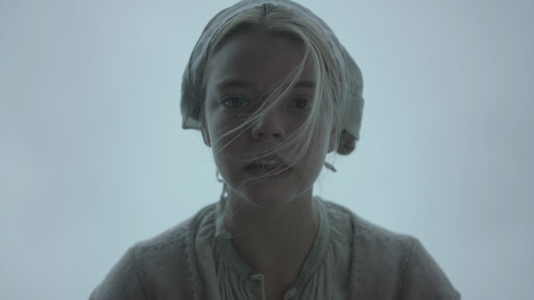 Anya Taylor-Joy as Thomasin in The Witch, staring down at the camera with her hair in her eyes