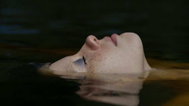 Mia Goth as Maxine floating in a lake with her eyes closed in X