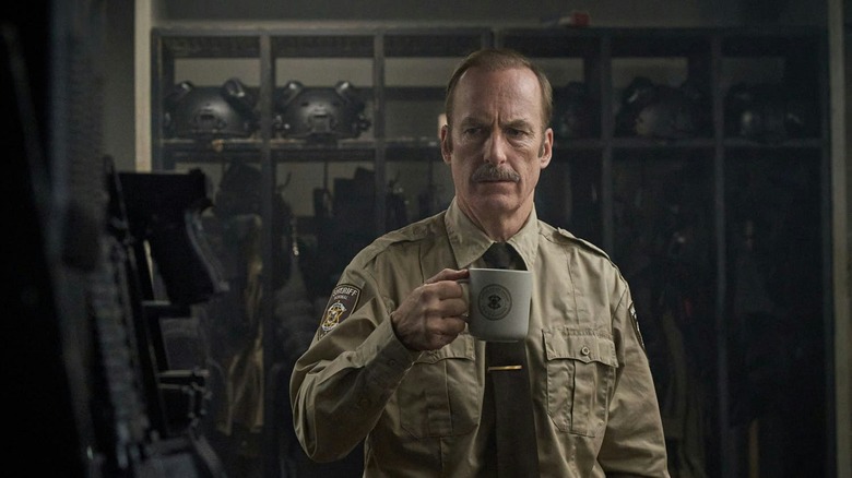 Bob Odenkirk as Ulyesses drinking coffee in an armory in Normal