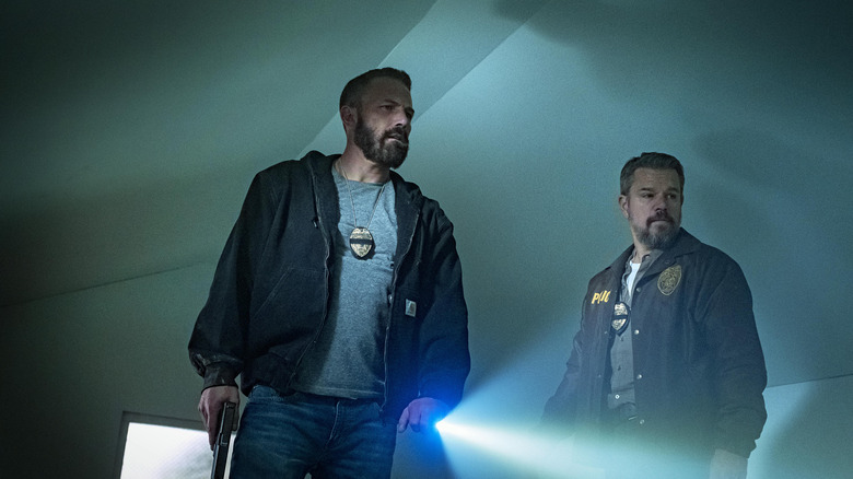 Ben Affleck as Sergeant J.D. Byrne and Matt Damon as Lieutenant Dane Dumars with flashlights looking at a wall in The Rip
