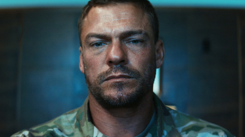 81 standing in a dark room in "War Machine."