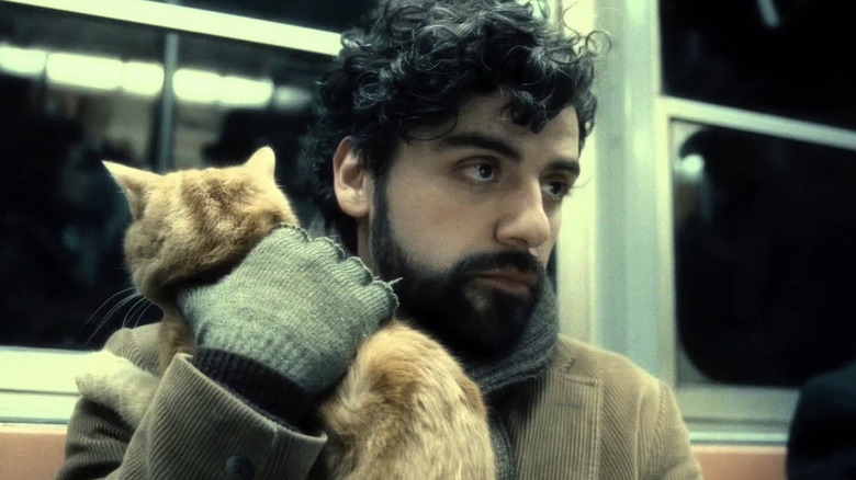 Oscar Isaac as Llewyn Davis holding a cat on the subway in Inside Llewyn Davis