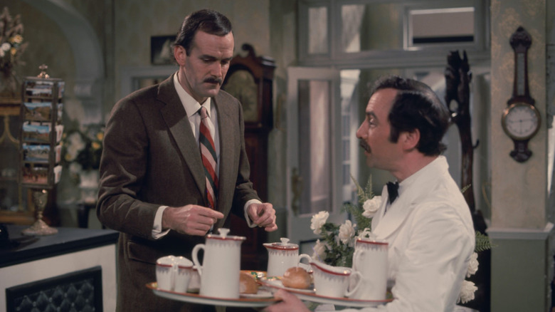John Cleese as Basil Fawlty helping waiter Manuel (Andrew Sachs) in Fawlty Towers