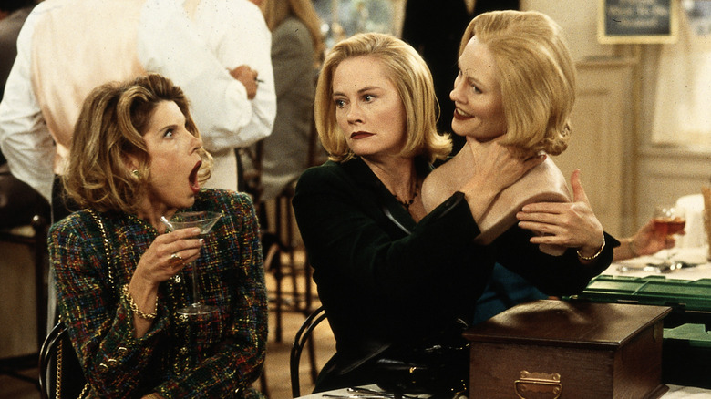 Maryann and Cybill shocked at a table as Cybill holds a model of her own head