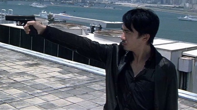 Chan Wing-yan (Tony Leung) points a pistol directly at the head of Lau Kin-ming (Andy Lau) on a roof overlooking Hong Kong in Infernal Affairs