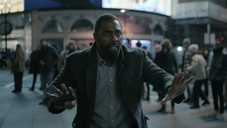 John Luther (Idris Elba) stands with his hands outstretched on a crowded street corner in Luther: The Fallen Sun