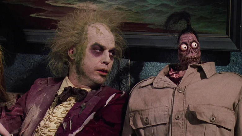 Michael Keaton as Beetlejuice next to torso with shrunken head in Beetlejuice