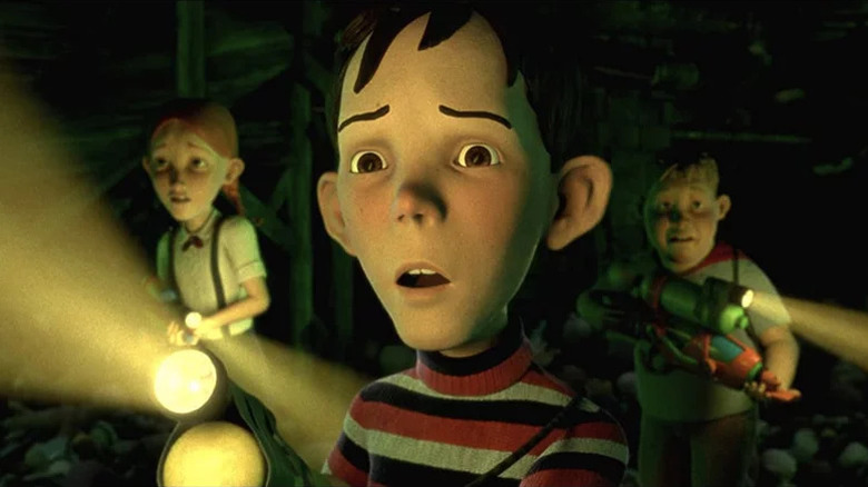 Two animated boys and one girl holding flashlights and looking scared in dark room in Monster House