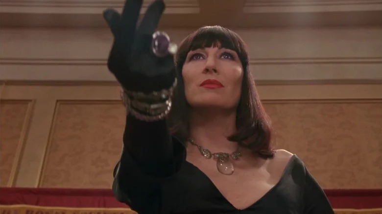 Anjelica Huston in velvet dress holding out gloved hand in The Witches