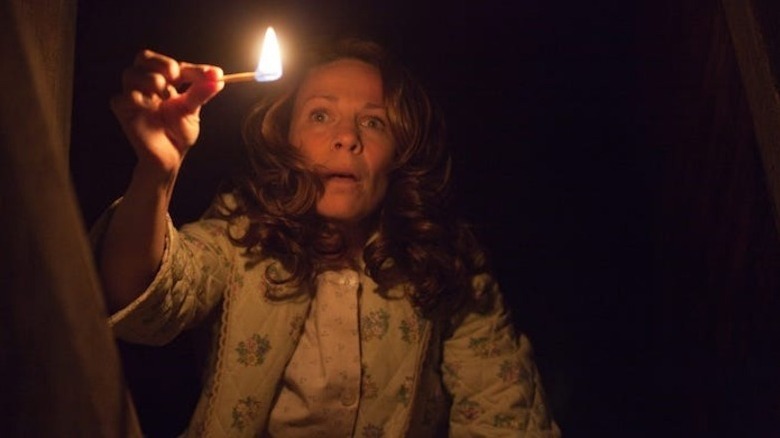 Carolyn Perron (Lili Taylor) holds a lit match in the dark in The Conjuring