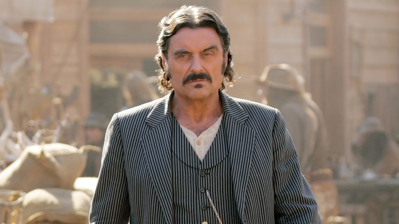 Ian McShane as Al Swearengen, scowling in town in Deadwood.