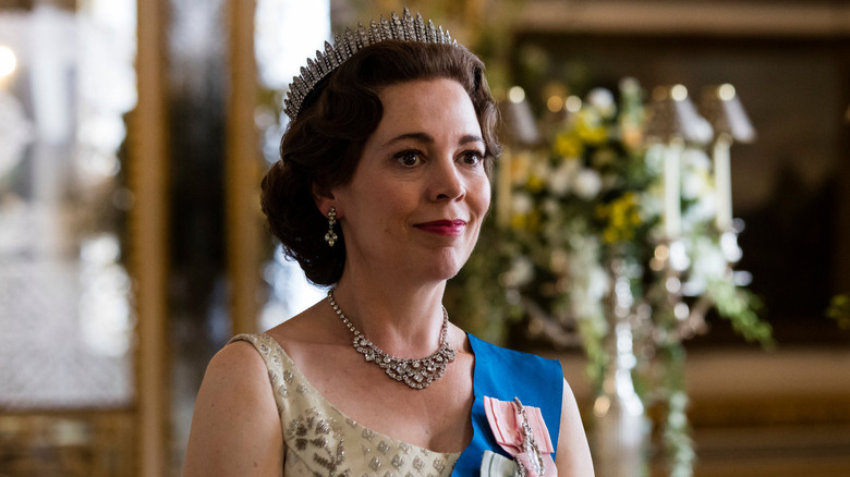 Olivia Colman as Queen Elizabeth II, smiling softly in The Crown.