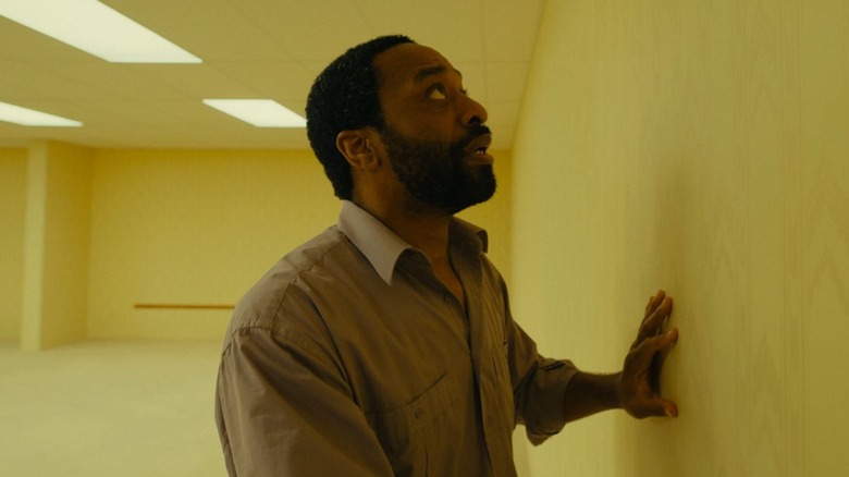 Chiwetel Ejiofor as Clark touching one of the yellow walls in Backrooms