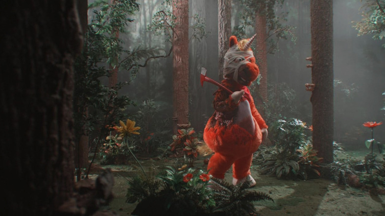 Buddy stands in the woods with an axe in Buddy