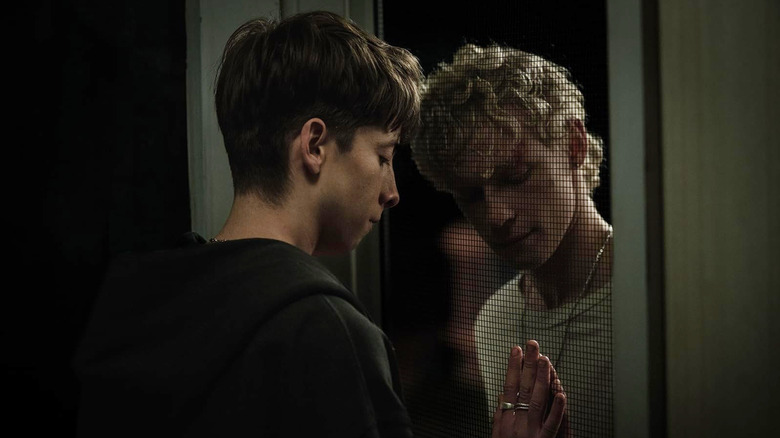 Naim and Ryan pressing their palms together with a metal screen between them in Leviticus