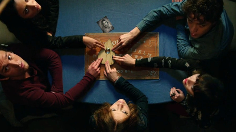 The friends looking up as they play with the Ouija board in Ouija