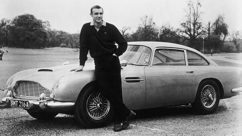 Sean Connery stands in front of his Aston Martin DB5 in Goldfinger