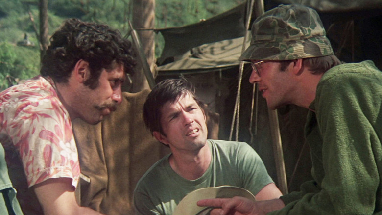 Trapper John (Elliot Gould) conspires with Hawkeye (Donald Sutherland) as Duke (Tom Skerritt) watches in M*A*S*H