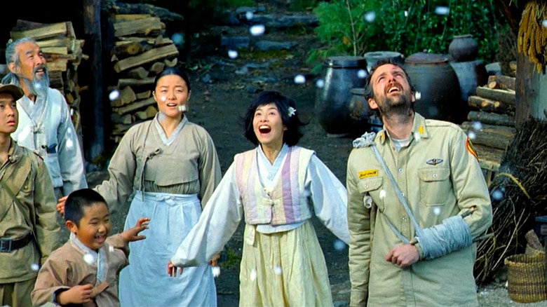 Yeo-il (Kang Hye-jung) and Neil Smith (Steve Taschler) look up with villagers and soldiers at falling popcorn in Welcome to Dongmakgol