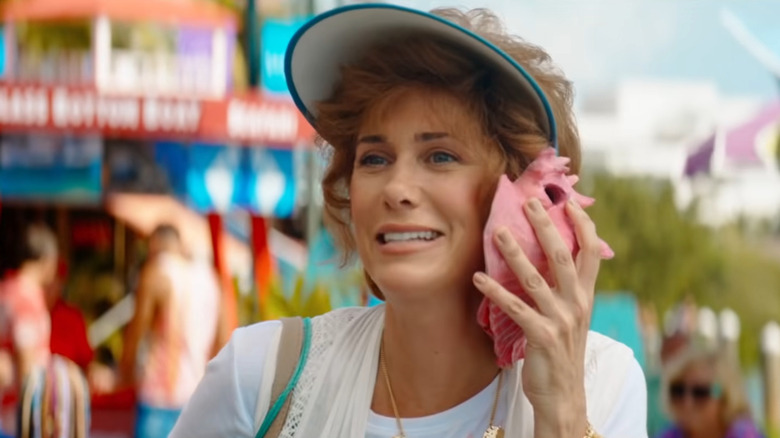 Kristen Wiig holding pink shell to her ear in Barb & Star Go To Vista Del Mar