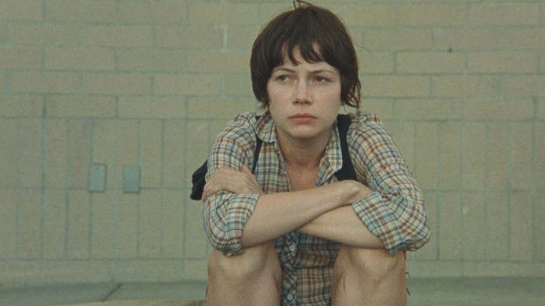 Michelle Williams with short dark hair sitting down in Wendy and Lucy