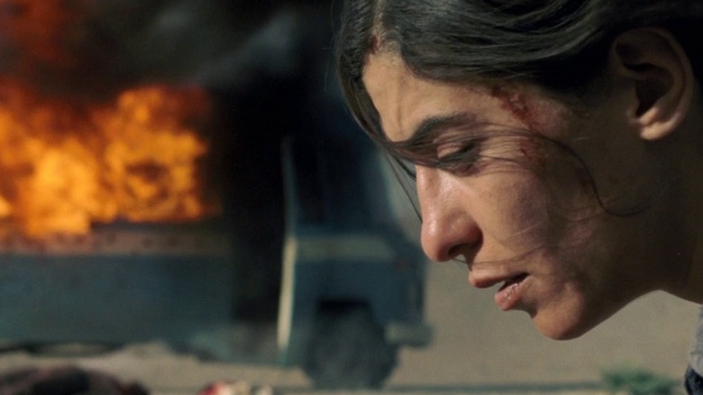 Mélissa Désormeaux-Poulin as Jeanne kneeling on ground with exploded van behind her in Incendies.