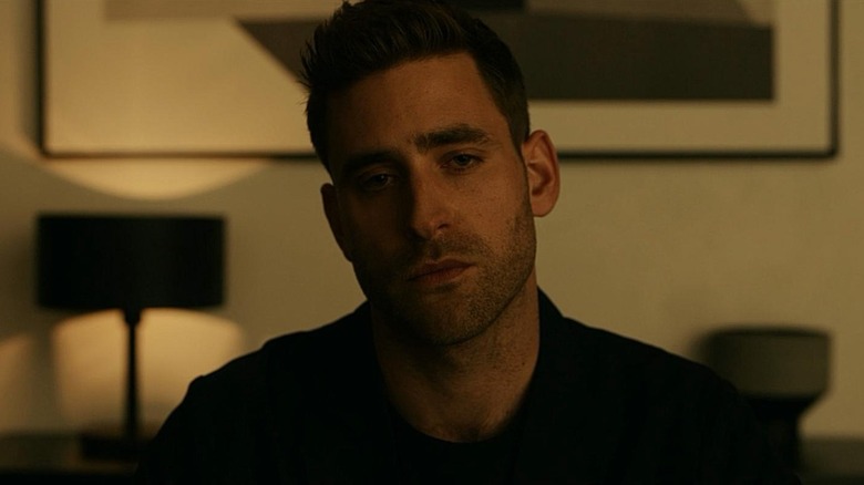 Oliver Jackson-Cohen as Adrian Griffin in The Invisible Man, looking somberly past the camera.