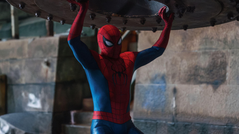 Tom Holland as Spider-Man lifting up a heavy piece of metal oer his head in Spider-Man: Brand New Day