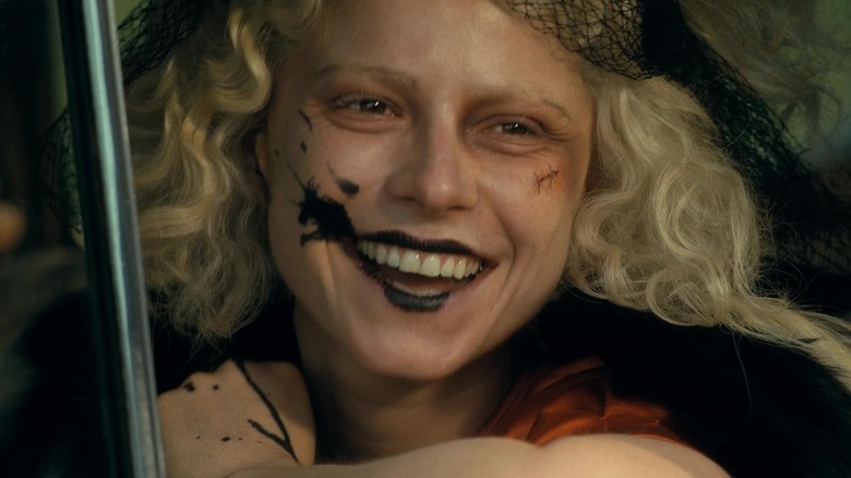 Jessie Buckley as The Bride smiling while sitting in a car in The Bride!