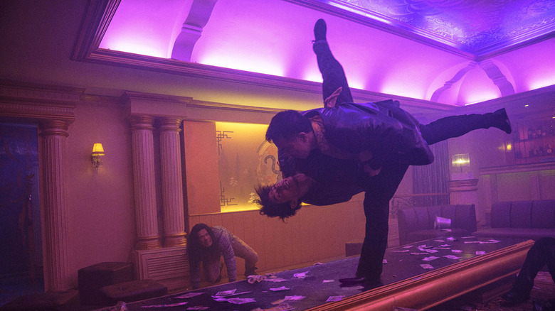 Navin body slams a guy in a neon-lit room in The Furious