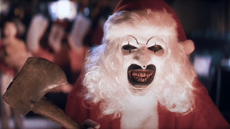David Howard Thornton as Art the Clown smiling in a Santa suit in Terrifier 3