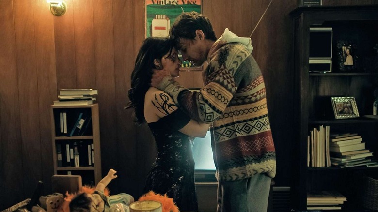 Inde Navarrette as Nikki Freeman and Michael Johnston as Bear, embracing in front of a television in Obsession.