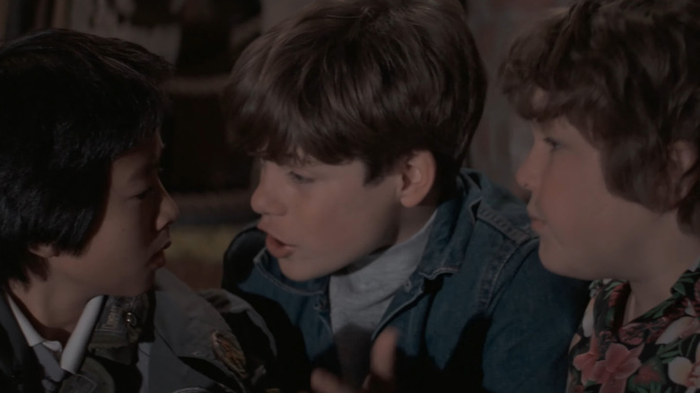 Ke Huy Quan, Sean Astin, and Jeff Cohen as Data, Mikey, and Chunk talking together in The Goonies