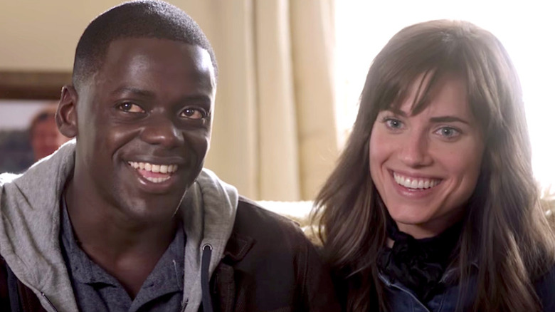 Chris Washington (Daniel Kaluuya) and Rose Armitage (Allison Williams) smile on a couch in Get Out