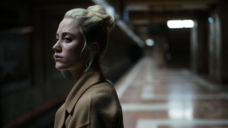 Julia (Maika Monroe) stands alone in a train station in Watcher