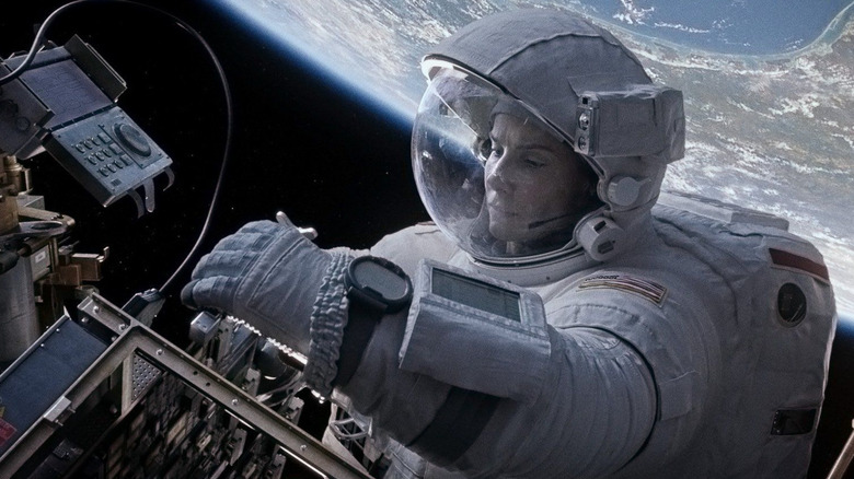 Ryan Stone (Sandra Bullock) makes repairs in Earth's orbit while in a spacesuit in Gravity (2013)