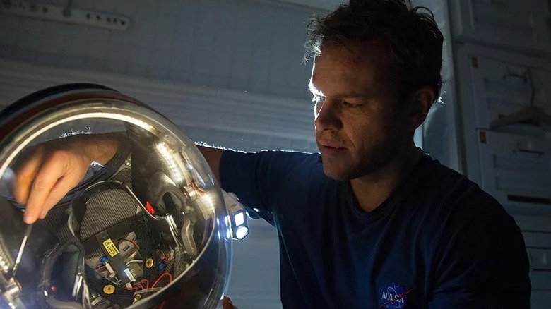 Mark Watney (Matt Damon) fixes a spacesuit helmet in The Martian