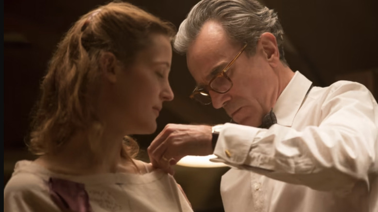 Daniel Day Lewis and Vicky Krieps as Reynolds Woodcock and Alma Elson as he works on her dress in Phantom Thread