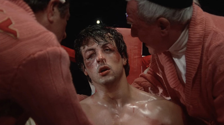 Sylvester Stallone as Rocky Balboa sits in the corner of the boxing ring, beaten up, in Rocky