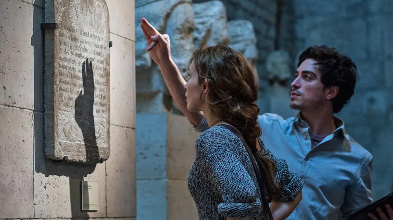 Scarlett and George reading a sign in the catacombs in As Above, So Below