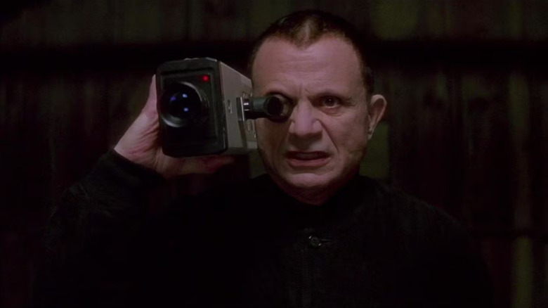 The Mystery Man filming someone with a camcorder and scowling in Lost Highway