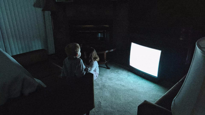 Kids watching a TV in a dark room in Skinamarink