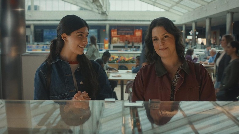 Sunny Sandler as Sophie Birenbaum smiling at Melanie Lynskey as Elizabeth Birenbaum in a mall food court in Don't Say Good Luck