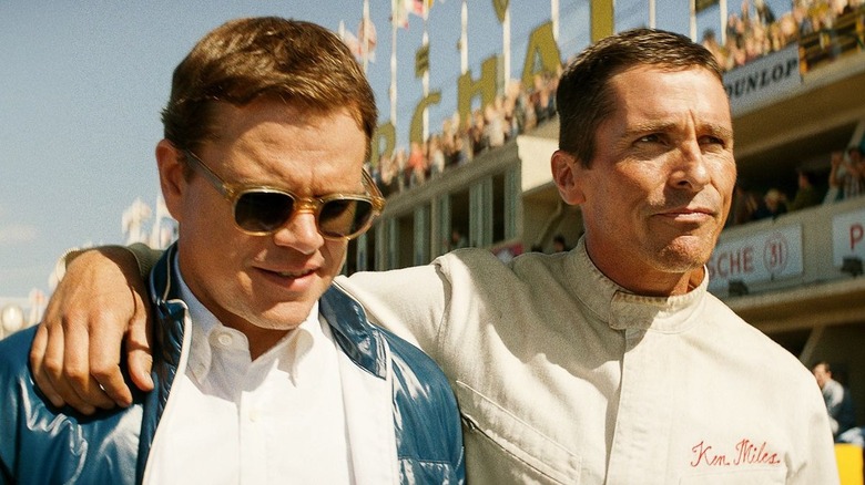 Ken Miles (Christian Bale) puts his arm around Carroll Shelby (Matt Damon) on the race track in Ford v Ferrari