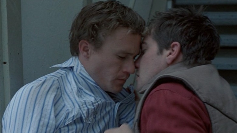 Jake Gyllenhaal as Jack Twist pulling in Heath Ledger as Ennis Del Mar for a kiss in Brokeback Mountain