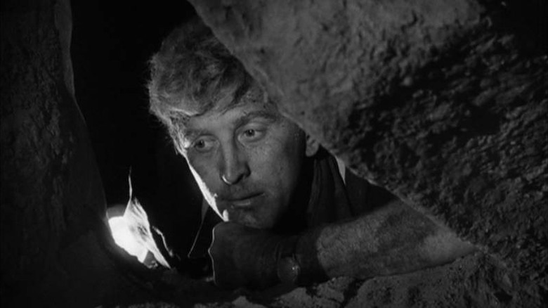 Charles Tatum (Kirk Douglas) poking his head through a crevice in Ace in the Hole