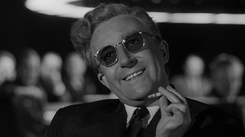 Dr. Strangelove (Peter Sellers) smiling while holding a cigarette in Dr. Strangelove
