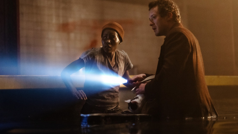 Sam (Lupita Nyong'o) looks back as Eric (Joseph Quinn) shines a flashlight in A Quiet Place: Day One