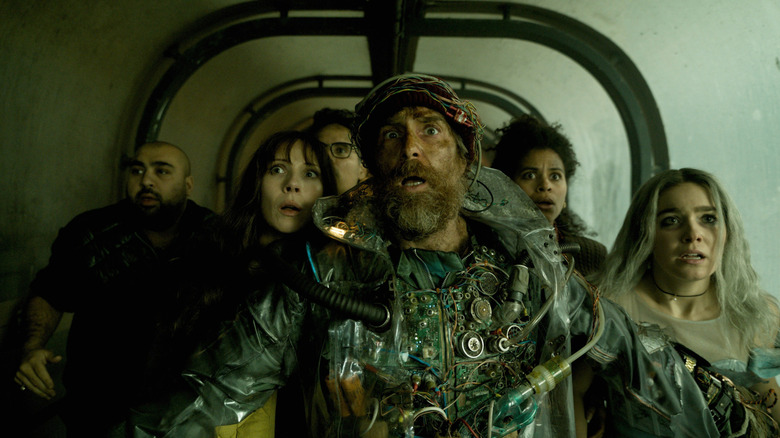 Sam Rockwell as the Man from the Future walking through a hallway in front of Asim Chaudhry as Scott, Juno Temple as Susan, Michael Peña as Mark, Zazie Beetz as Janet, and Haley Lu Richardson as Ingrid in Good Luck, Have Fun, Don't Die